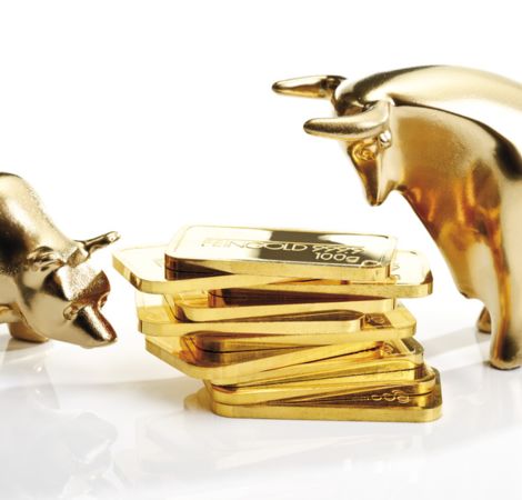 Goldene Figuren eines Bären und eines Stiers stehen um einen Stapel kleiner Goldbarren.